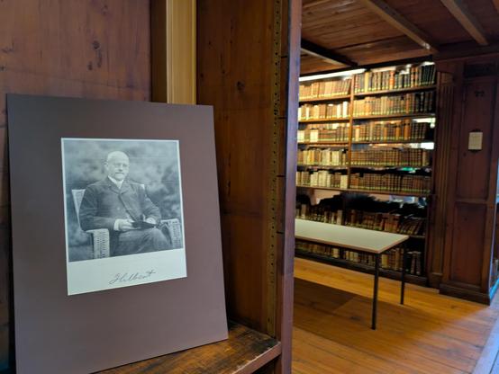 Nische im Heynesaal der historischen SUB, in einer Alkoven sieht man ein Foto von Hilbert stehen, im Hintergrund Bücherregale