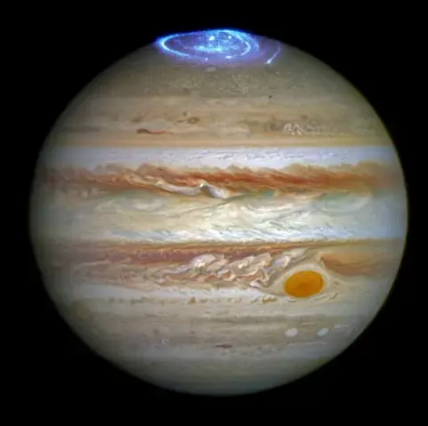 Die runde Jupiterscheibe füllt fast das gesamte Bild aus, nur die freien Ecken sind schwarz. Auf der Oberfläche des Planeten sind horizonal vielfarbige Wolkenbänder zu sehen, die gelblich, weiß, orange oder rötlich und selten blassblau erscheinen. Die Bänder sind in sich verwirbelt und teilweise mit Flecken durchsetzt. Einer dieser Wirbel ist besonders groß und auffällig orangerot. Er befindet sich in der unteren rechten Seite der Scheibe und wird begleitet von einem ausgerägten Wirbelfeld dire…