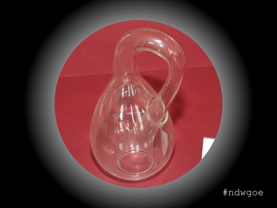 Foto einer Kleinschen Flasche vor roten Hintergrund. Die Kleinsche Flasche ist ein klassisches Beispiel einer nichtorienterbaren Fläche.