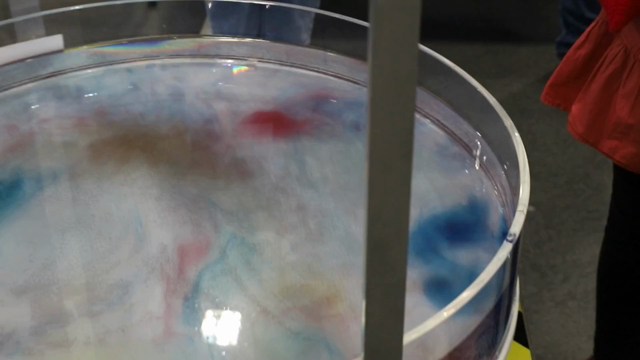 Video of a large round tube of water spinning around with color drops crating swirls and bands of color