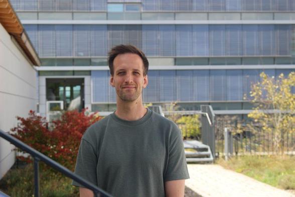 Christian Renggli receives an ERC Starting Grant. The photograph shows Christian on a rooftop terrace with the window front of a building in the background. Christian is looking straight into the camera and is smiling.