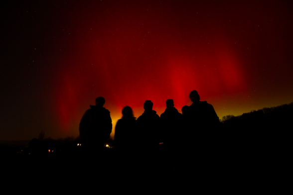 red sky behind silhouette of 6 people