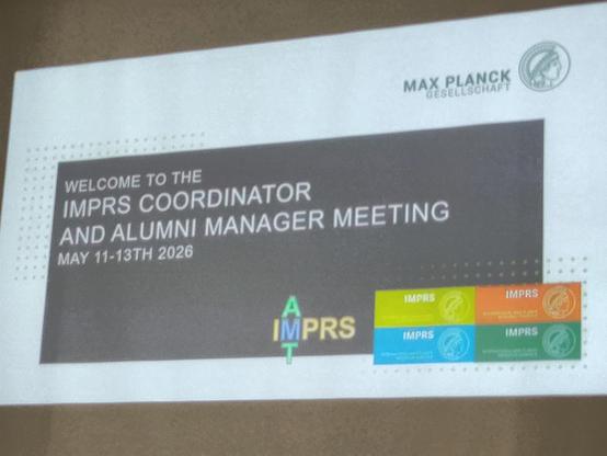 A projected title slide of a talk sporting the Max Planck society logo, the IMPRS logo in various colors, and the title of the event "IMPRS coordinator and alumni manager meeting" plus the date given as 11-13 May.